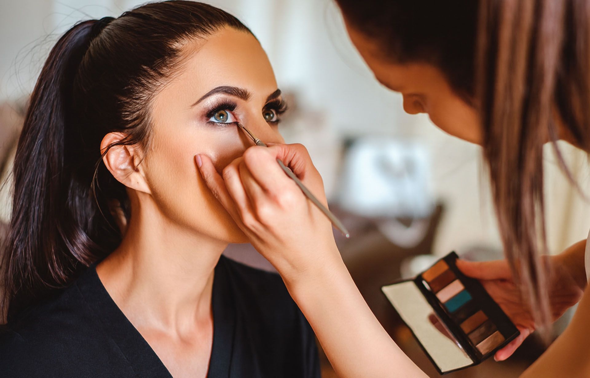 Esthetics program student applying eye makeup with a fine brush during hands-on training
